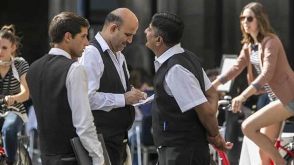 Tres camareros, durante su jornada laboral en un establecimiento de la plaza Reial de Barcelona.