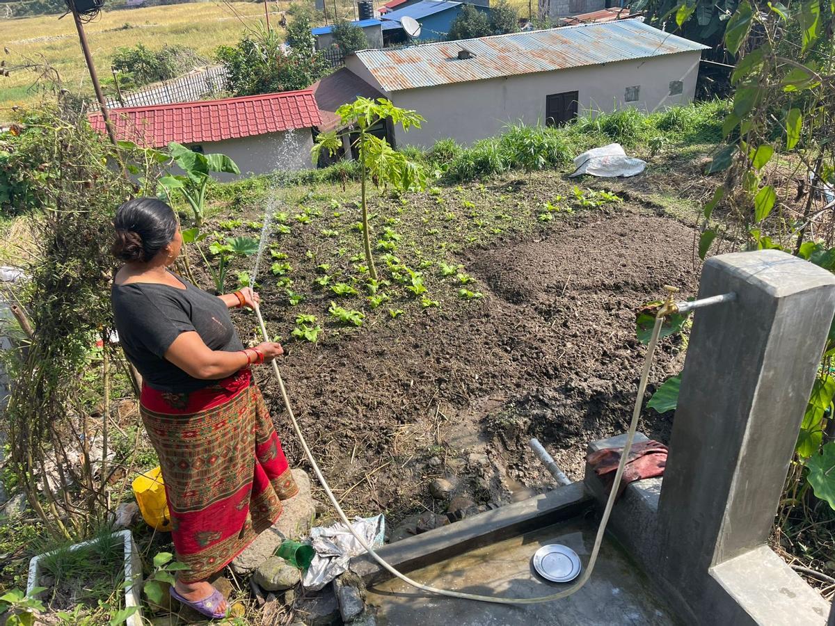 Una mujer regando el huerto en su comunidad en Nepal