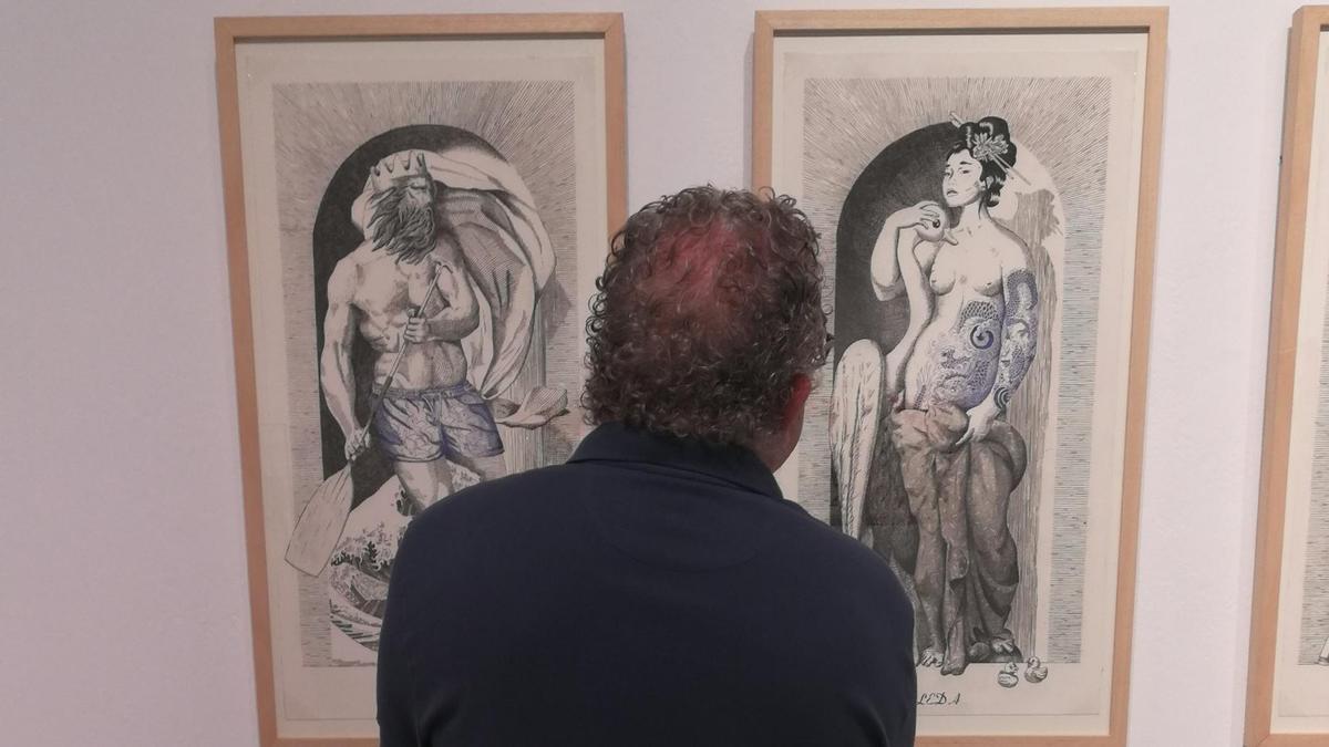 Una persona contempla dos obras de la muestra  colectiva.
