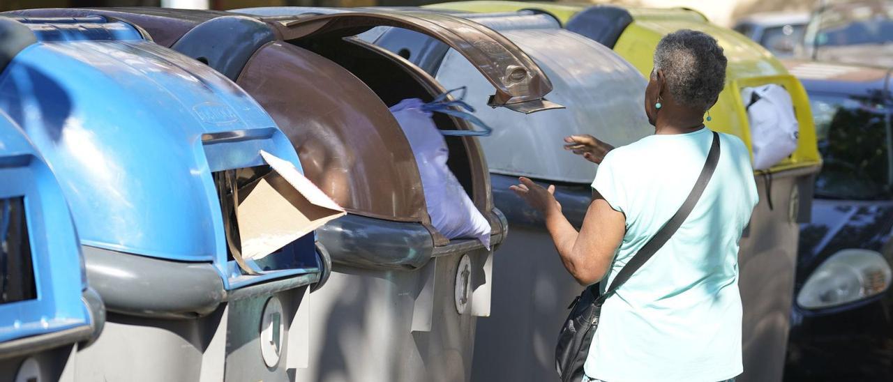 Una dona deixa una bossa amb deixalles al contenidor de matèria orgànica.  | MARC MARTÍ