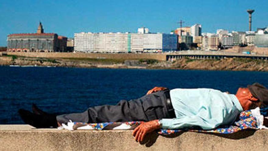 Un hombre duerme la siesta en una banco en el Paseo Marítimo de A Coruña.