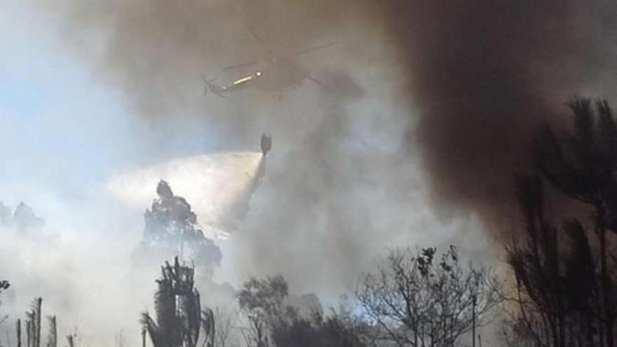 Dos jóvenes intentan apagar las llamas en el incendio que afectó a la parroquia de Silvoso.  // Snick