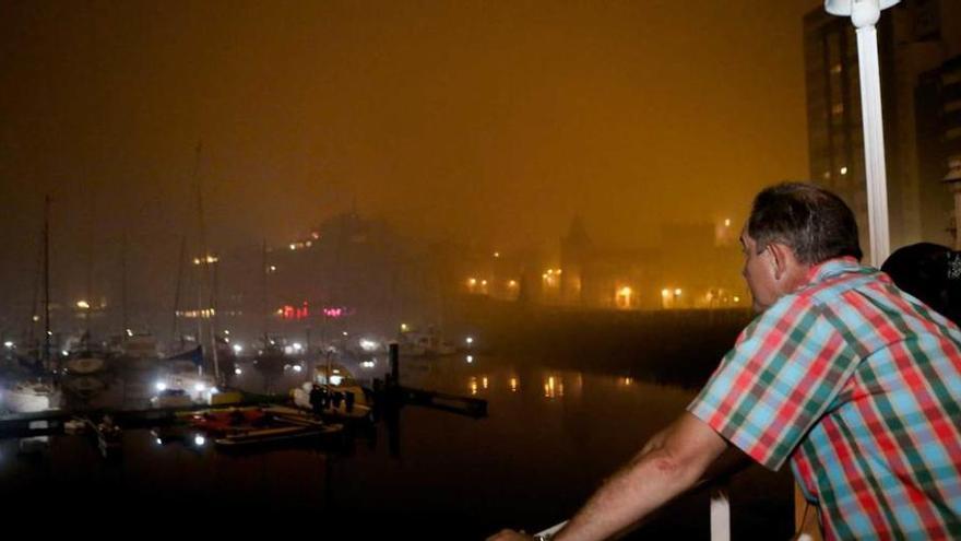 Un espectador observa los fuegos, deslucidos por la niebla, desde el puerto deportivo.