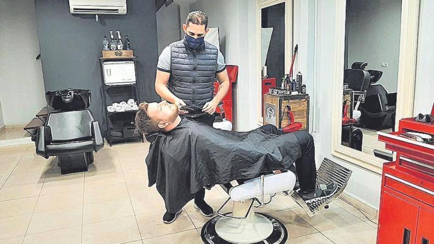 Vladimir Pérez con uno de sus clientes en la barbería.