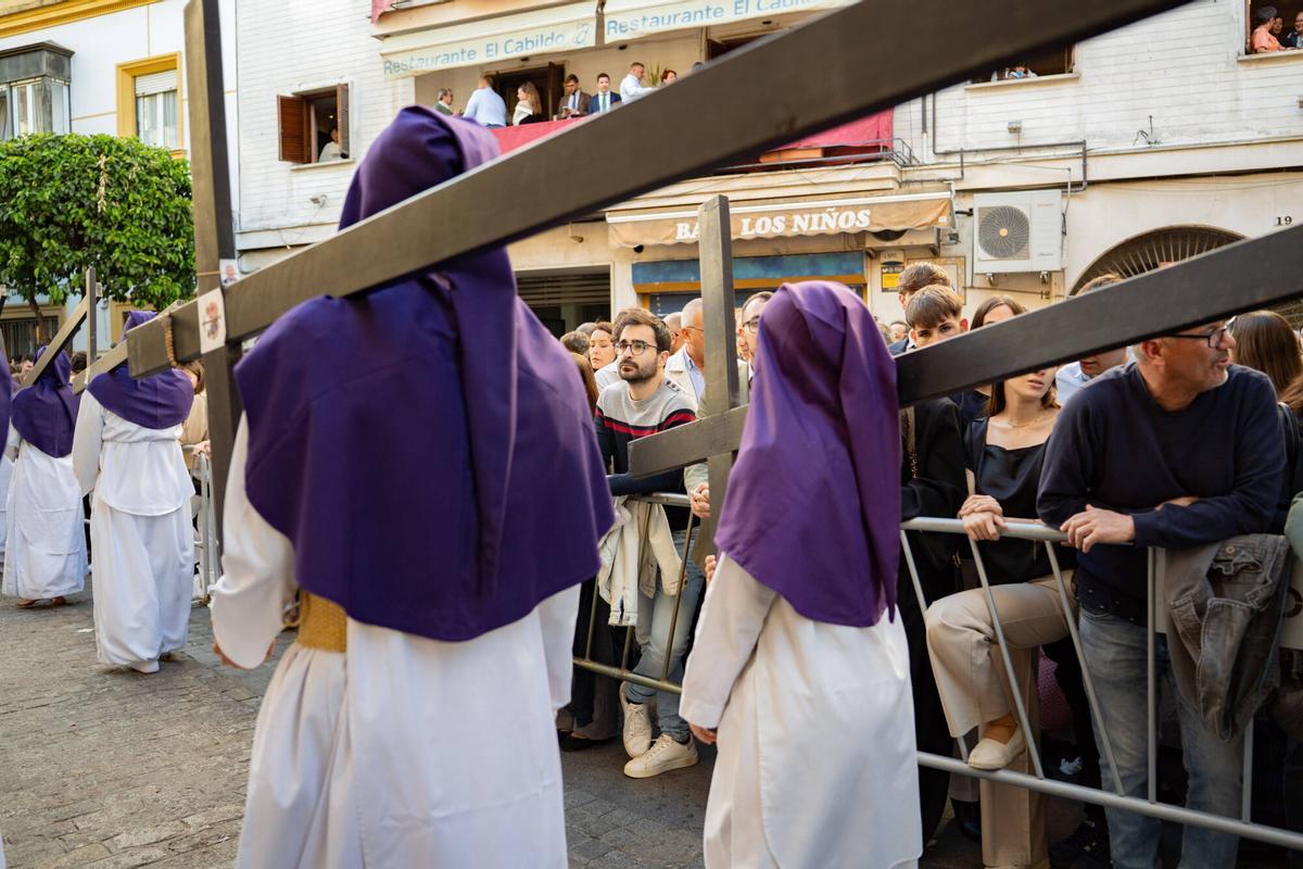 Penitentes de la Semana Santa de Sevilla y vallas para acotar el paso.