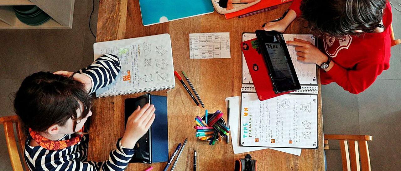 Dos escolares estudian en casa con sus cuadernos y consultando las tabletas. | EFE/KAI FÖRSTERLING