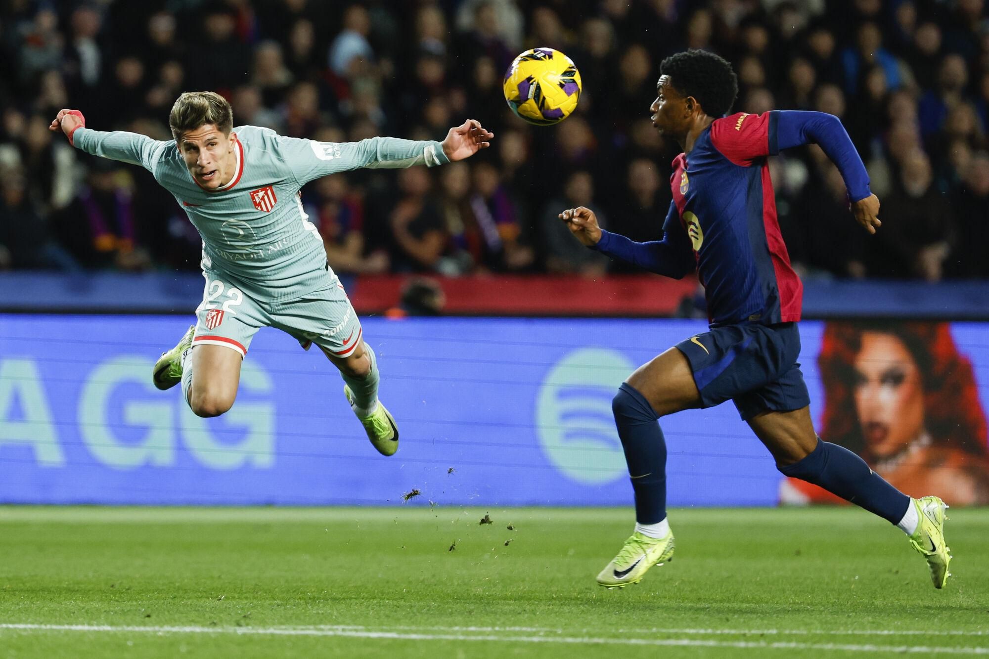 Atletico Madrid's Giuliano Simeone, left, duels for the ball with Barcelona's Alejandro Balde during the Spanish La Liga soccer match between Barcelona and Atletico Madrid at the Lluis Companys Olympic Stadium in Barcelona, Spain, Saturday, Dec. 21, 2024. (AP Photo/Joan Monfort). EDITORIAL USE ONLY/ONLY ITALY AND SPAIN