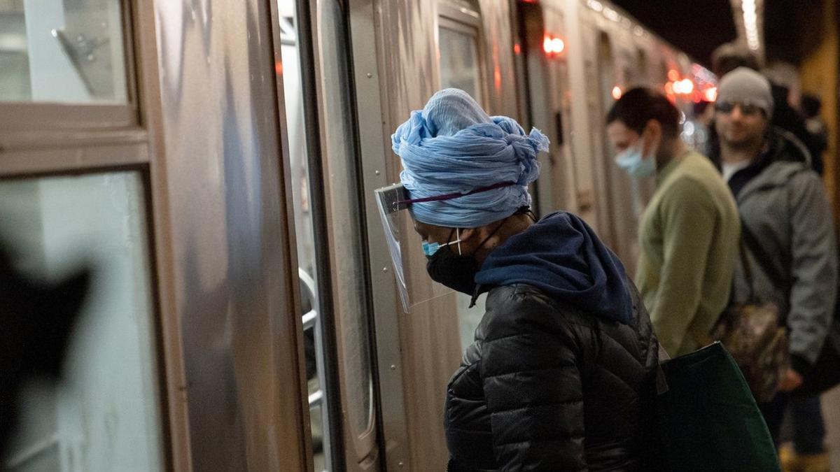 Una mujer con mascarilla y pantalla protectora en el metro de Nueva York.