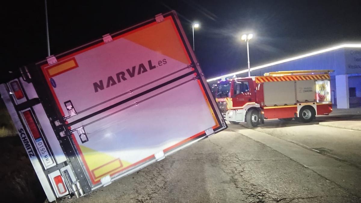 Aspecto del camión volcado y de la intervención de los bomberos de Benavente.