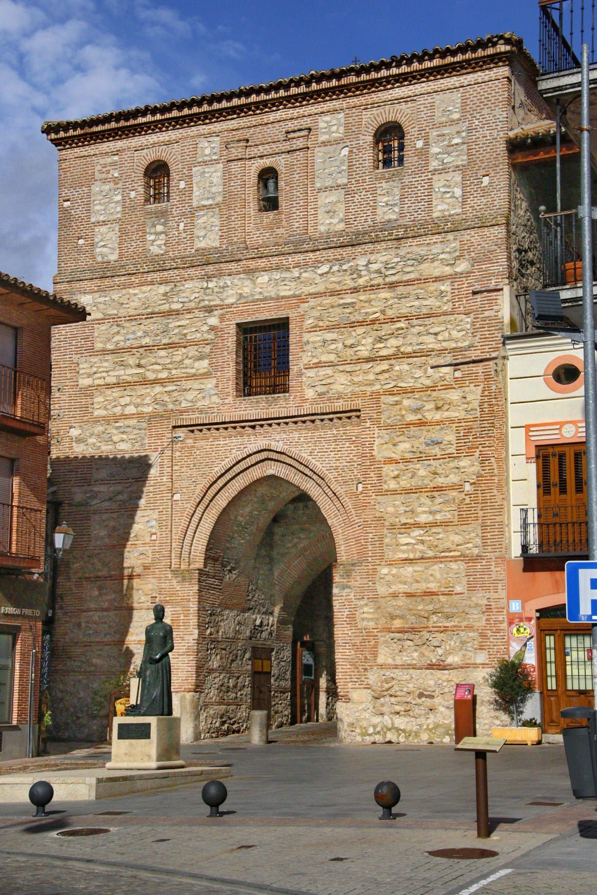 El imponente Arco del Alcocer y la estatua que conmemora a la reina Isabel I de Castilla