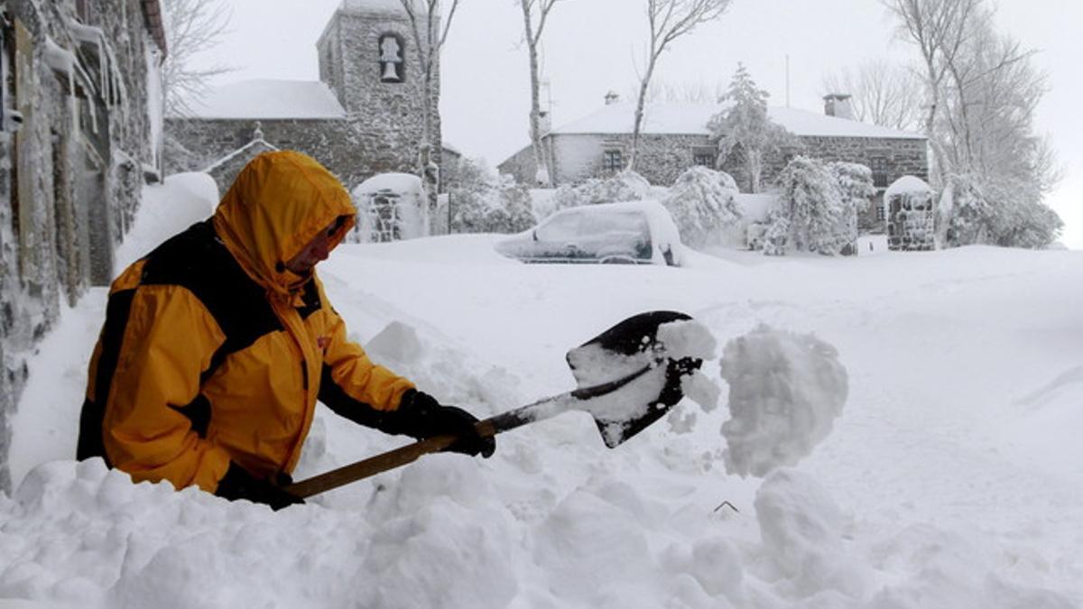 Un hombre despeja de nieve la entrada de un hostal con una pala en la población gallega de O Cebreiro.