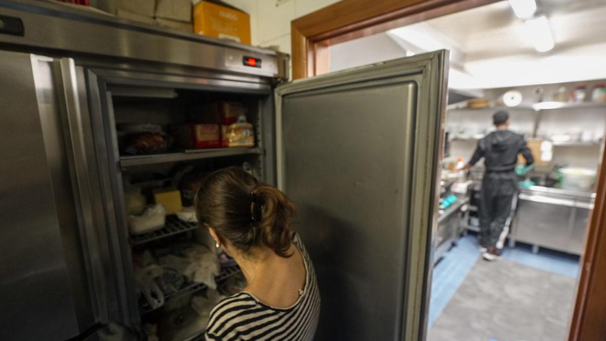 Una mujer comprueba el estado de la comida en una nevera en un restaurante de Barcelona, el día después del gran apagón.