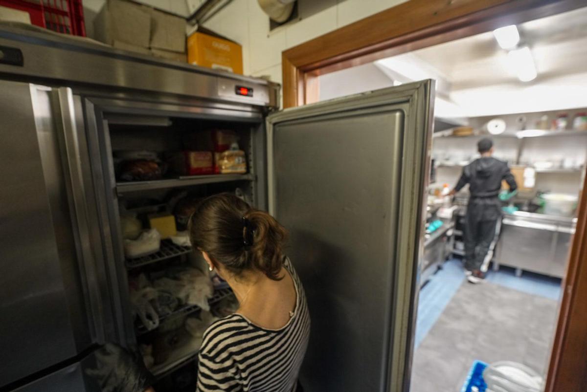 Una mujer comprueba el estado de la comida depositada en una nevera en un restaurante del centro de Barcelona, el día después del gran apagón.