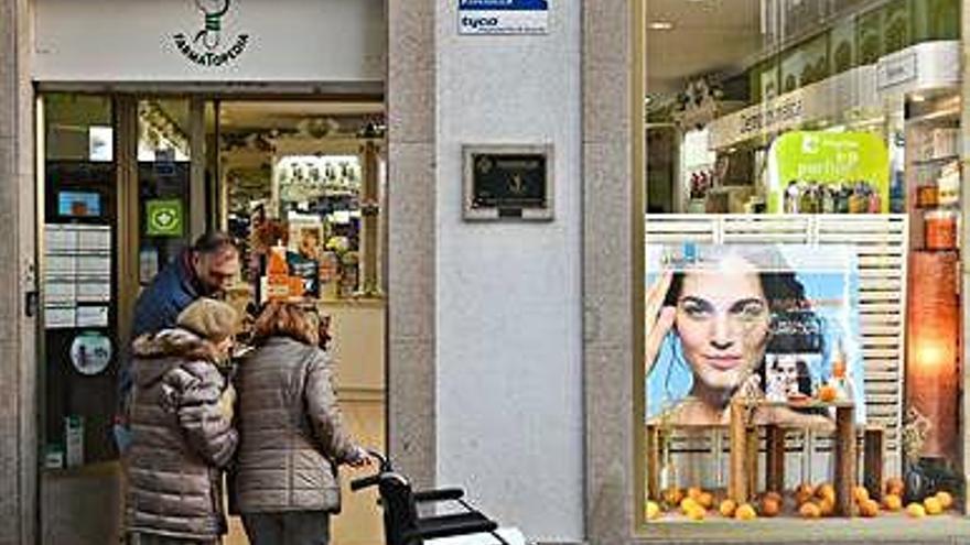 Dos personas mayores, ante una de las farmacias del centro.