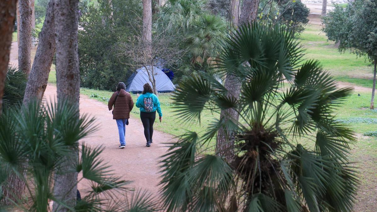 Vecinos de València pasean por el cauce del río Turia entre tiendas de campaña.