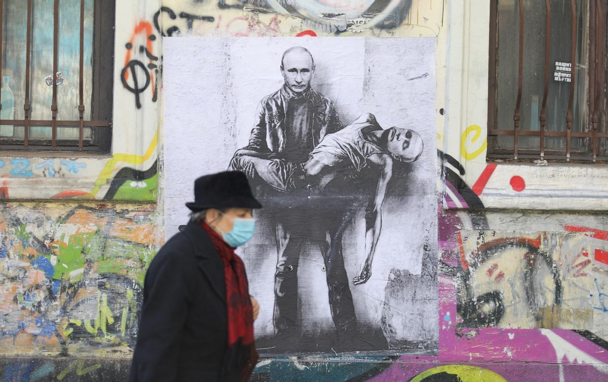 Una mujer pasa frente a un cartel que muestra al presidente ruso, Vladímir Putin, sosteniendo su propio cuerpo, en Sofía (Bulgaria).