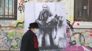 Una mujer pasa frente a un cartel que muestra al presidente ruso, Vladímir Putin, sosteniendo su propio cuerpo, en Sofía (Bulgaria).