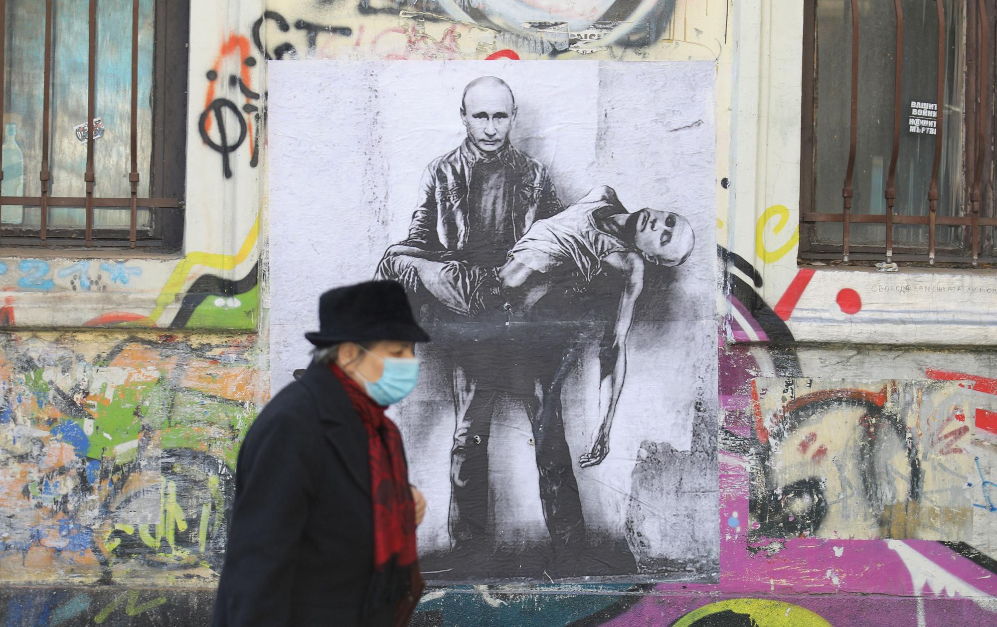 Una mujer pasa frente a un cartel que muestra al presidente ruso, Vladimir Putin, sosteniendo su propio cuerpo, mientras continúa la invasión rusa de Ucrania, en Sofía, Bulgaria.