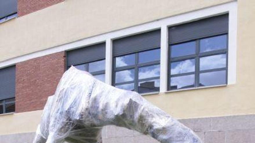 El artista Antonio Vázquez entre las patas de su escultura jirafa.