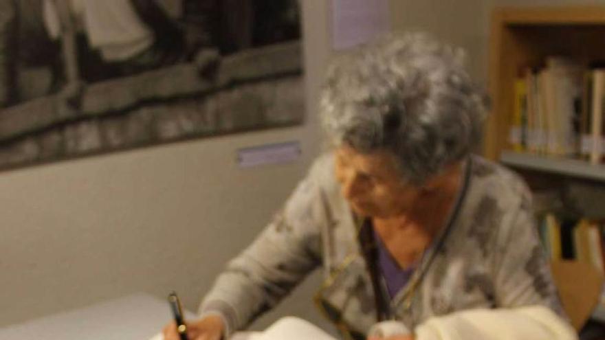 Asunción Carandell firma en el libro de visitas de la Casa de Cultura de Grado, con algunos de los poemarios publicados por Goytisolo sobre la mesa.