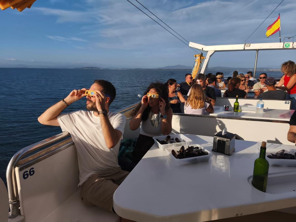 Pasajeros de una naviera observando el cielo con gafas preparadas para ver el eclipse de sol.