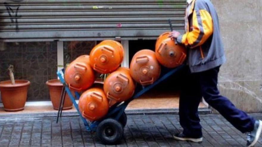 Un hombre carga con varias bombonas de butano.