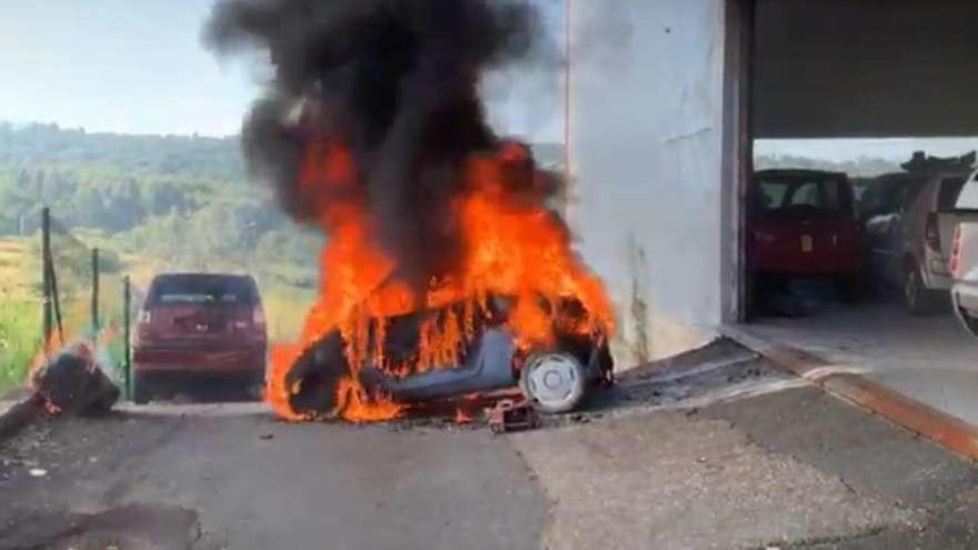 El vehículo sin carné arde en el exterior de la nave de la empresa. // Bombeiros de Deza