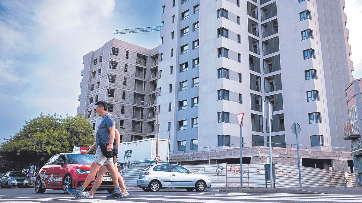 Dos transeuntes caminan por delante de un edificio en obras.