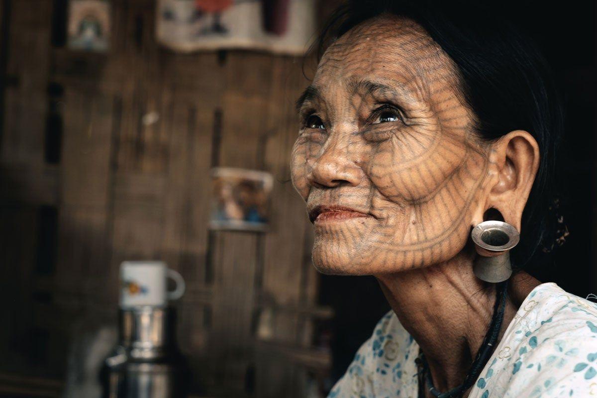 Mujer con la cara tatuada y las orejas perforadas en Myanmar, la antigua Birmania