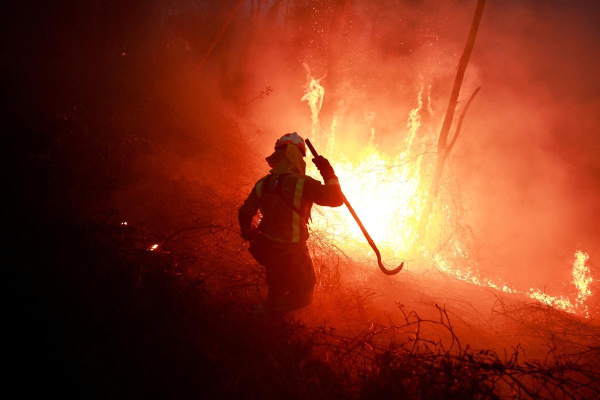 Un bombero gallego hace frente a las llamas en un bosque durante un brote de incendios forestales, en Piedrafita, Asturias