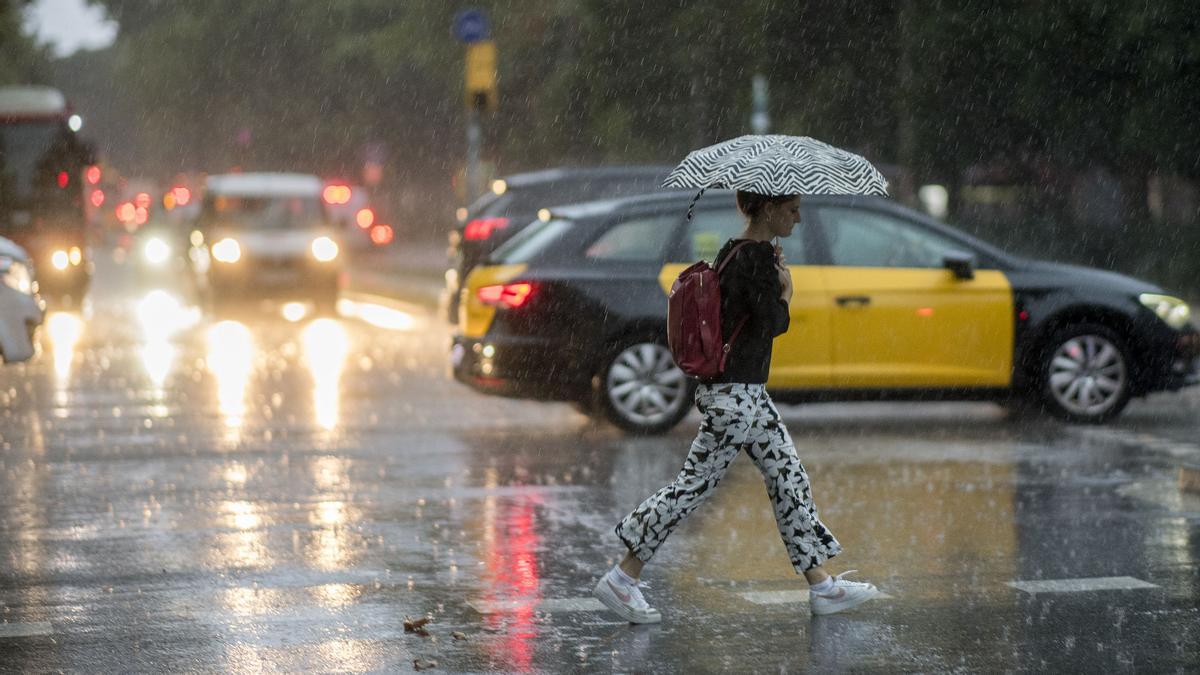 Barcelona 31.08.2022. Barcelona. Mujer con paraguas bajo la lluvia intensa sobre la ciudad de Barcelona a primera hora. Fotografía de Jordi Cotrina