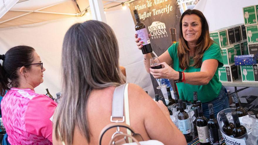 Una bodeguera sirve una copa de vino a varios asistentes.