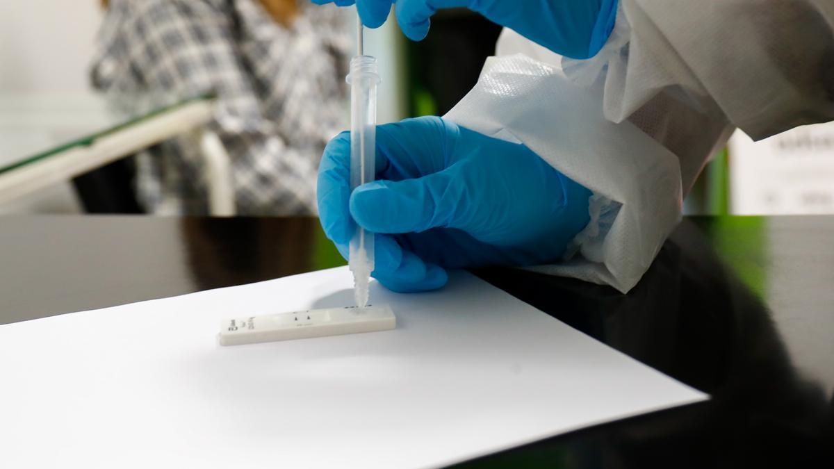 Una trabajadora sanitaria sostiene un test de antígenos.