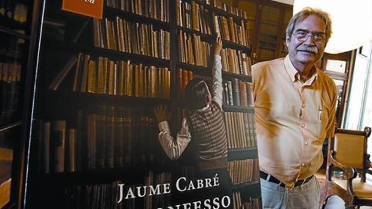 Jaume Cabré, ayer, en la sala Pompeu Fabra del Ateneu Barcelonès, contempla una reproducción de la cubierta de su última novela.