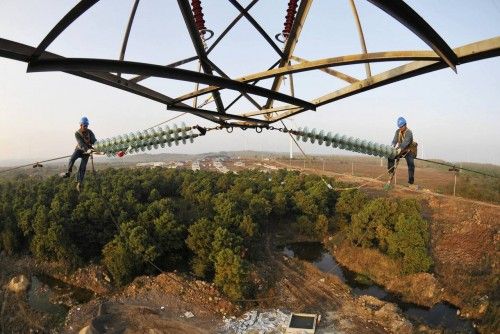 Labourers practise maintenance works on an electricity pylon in Zilaiqiao township of Mingguang