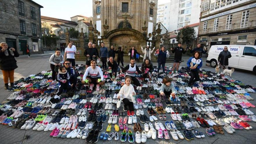 Promotores y colaboradores de la iniciativa junto a las más de mil zapatillas que recaudaron y expusieron ayer en la plaza de la Peregrina.  // Gustavo Santos