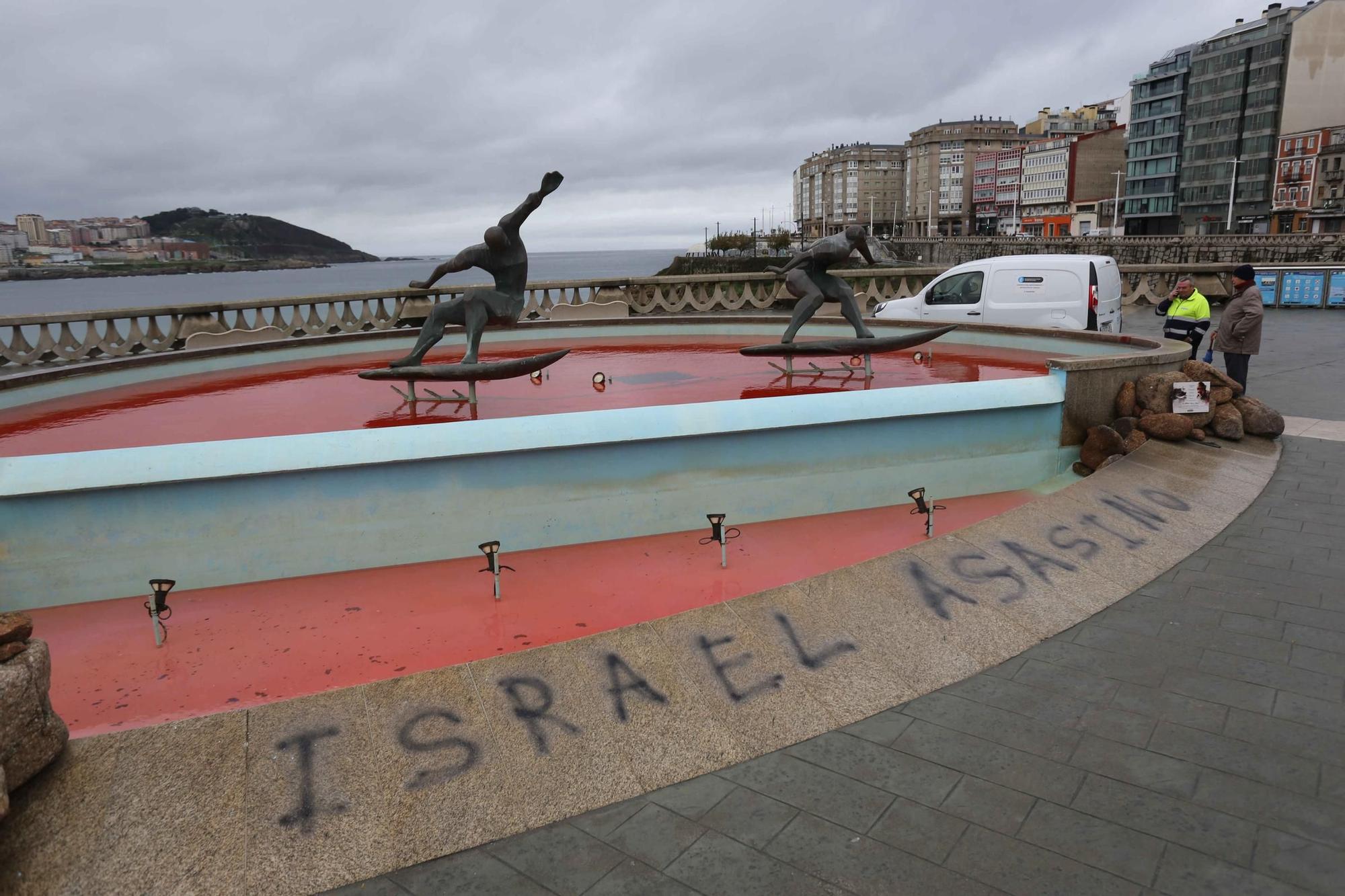 La fuente de los surfistas, con el agua teñida de rojo y una pintada contra Israel