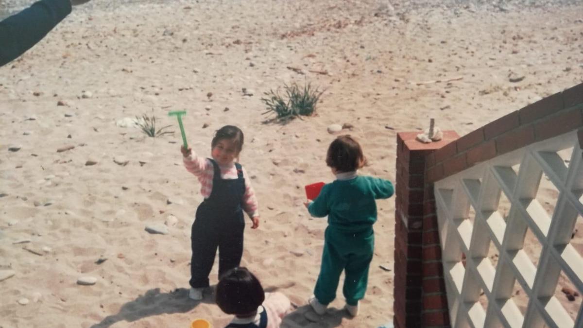 Mari Carmen Romero, de niña, jugando frente a las escaleras que ha destrozado el oleaje, en una imagen en la que apenas se aprecia el mar al fondo, por su lejanía.