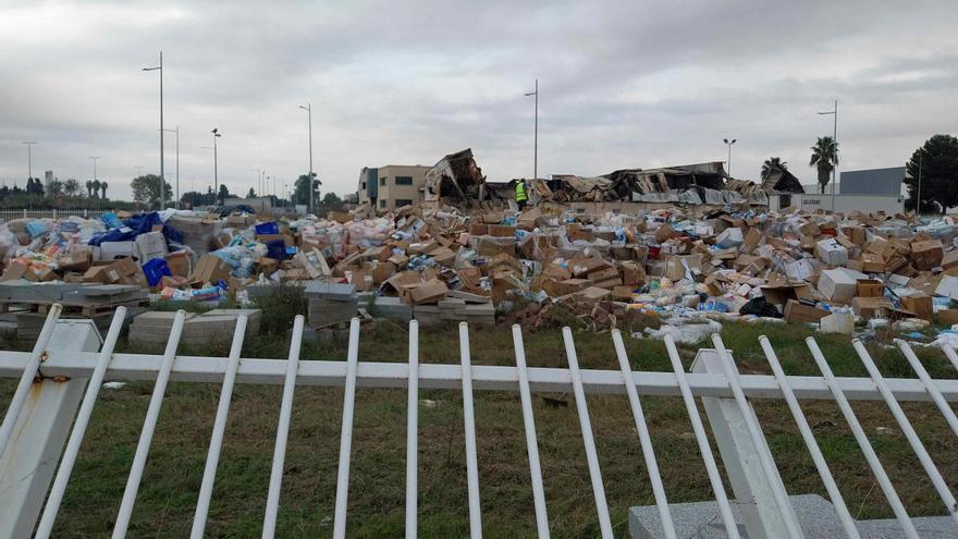 Una persona rebusca en la montaña de productos de limpieza en la que se han convertido los palets depositados en la campa.
