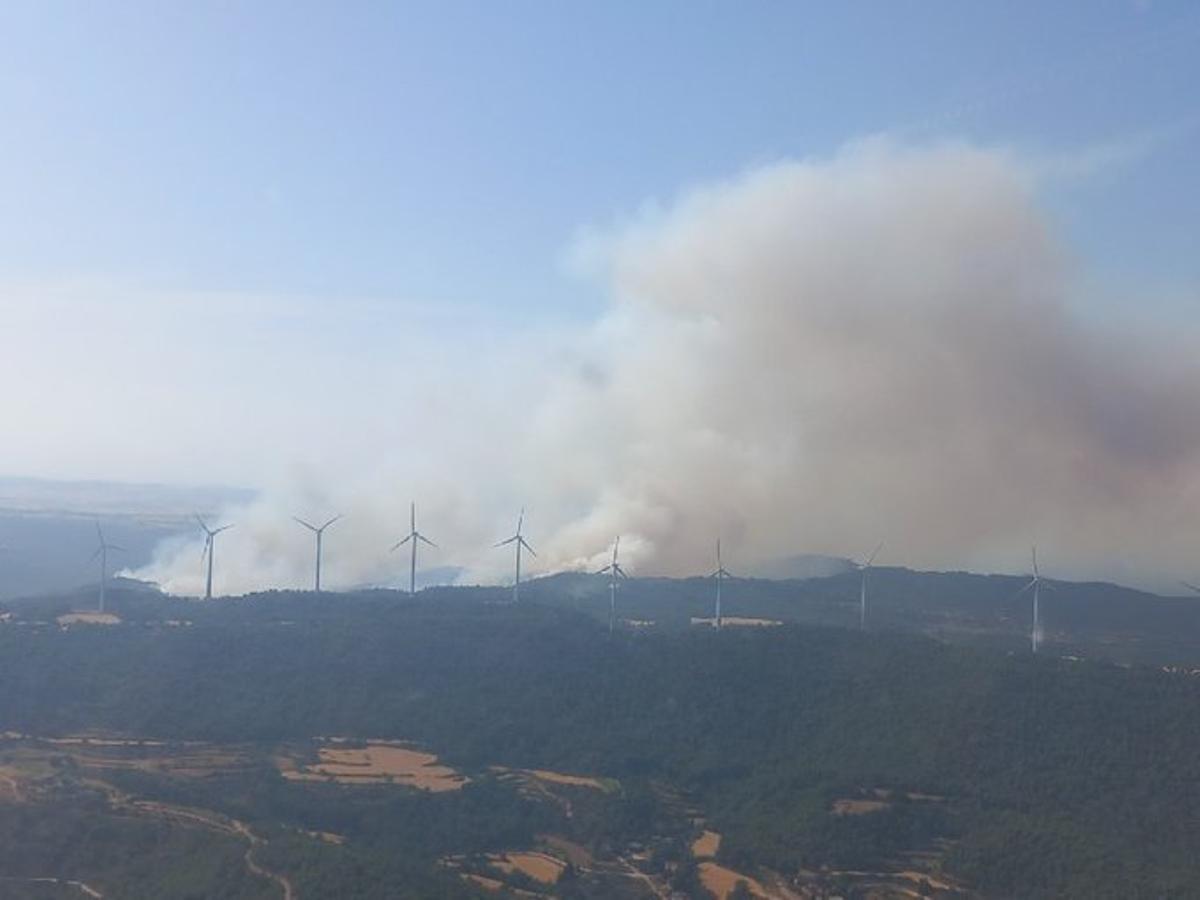 Els aerogeneradors del parc eòlic de la serra de Rubió i l'incendi al darrere