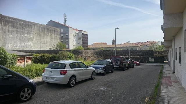 La calle Hortas Reais, con coches aparcados y la muralla del convento de las Dominicas al fondo. |