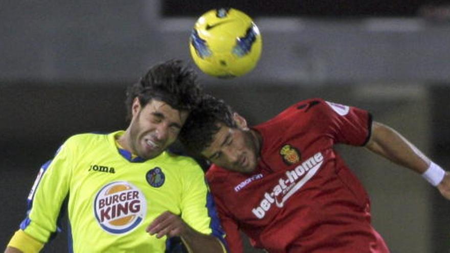 El defensa del Getafe CF Miguel Torres (i) lucha por un balón aéreo con el delantero israelí del RCD Mallorca Tomer Hemed.