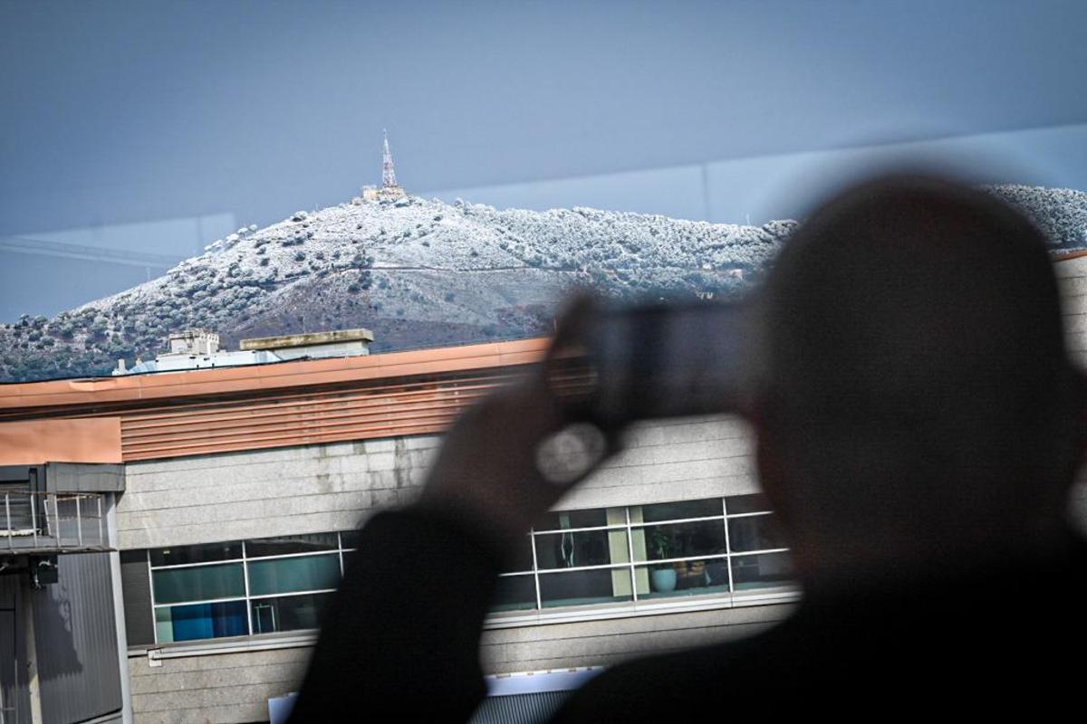 Asistentes al Mobile World Congress toman fotos de la nieve que ha caído esta mañana en Barcelona y ha cubierto de blanco Collserola