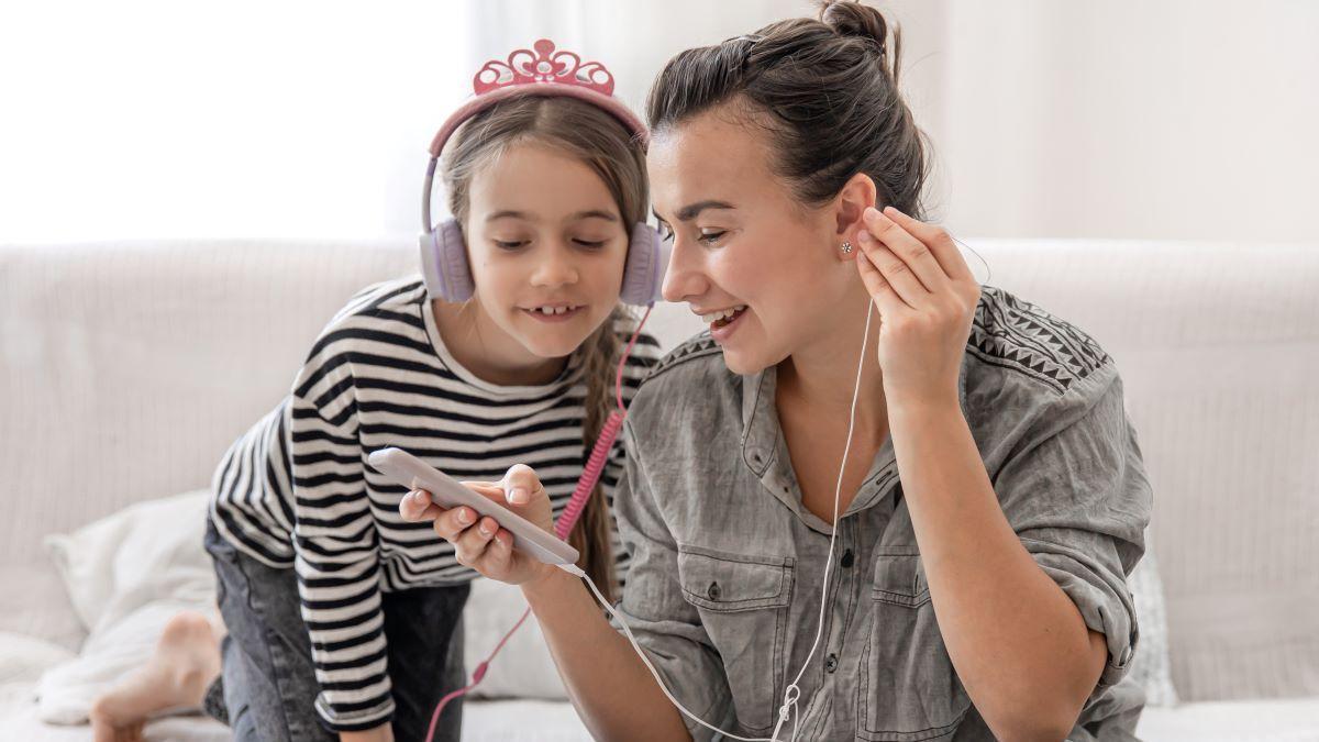 Madre e hija escuchando un podcast en una imagen de archivo.