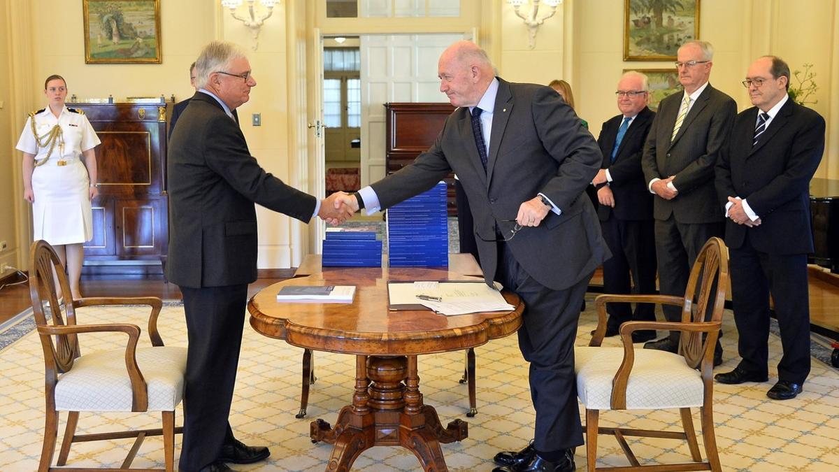 El comisionado de Justicia Peter McClellan (izquierda), y el gobernador general de Australia, Peter Cosgrove, se dan la mano tras la firma del documento final de la comisión especial de la pederastia en Australia.