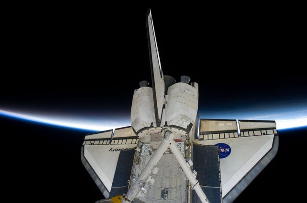 Els reptes espacials segueixen estan plens de ministeris, però per ara els humans ens conformem de veure la Terra des de fora. A la foto elShuttle Discoveryinterromp la visió de la línia de l’atmosfera de la Terra.