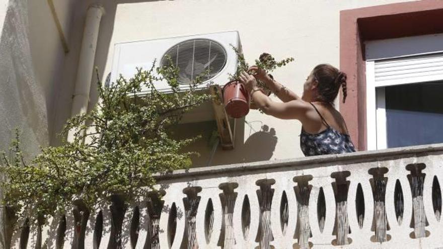 Una mujer supervisa el aparato de aire acondicionado en la terraza de su vivienda.