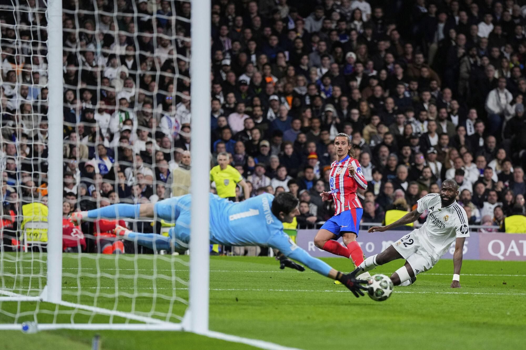 Real Madrid's goalkeeper Thibaut Courtois, left, makes a save in front Atletico Madrid's Antoine Griezmann, center, during the Champions League round of 16 first leg soccer match between Real Madrid and Atletico Madrid at the Bernebeu stadium in Madrid, Spain, Tuesday, March 4, 2025. (AP Photo/Manu Fernandez). EDITORIAL USE ONLY / ONLY ITALY AND SPAIN