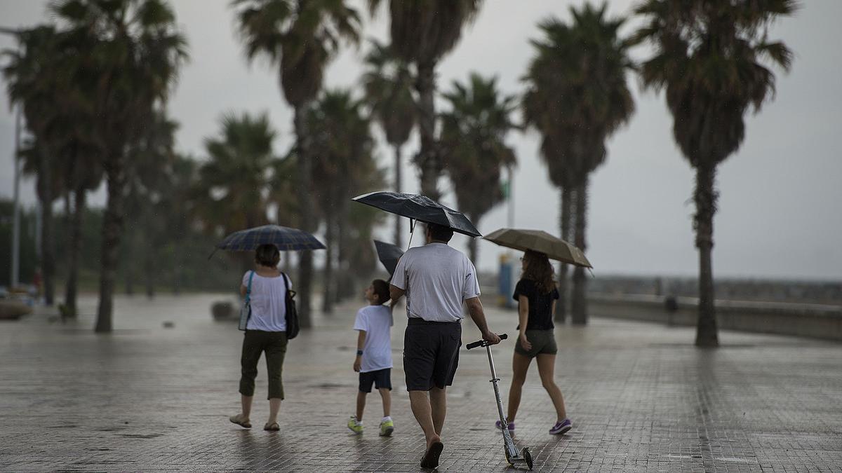 Una familia se protege de la lluvia en la playa del Fòrum de Barcelona, en agosto del 2014.