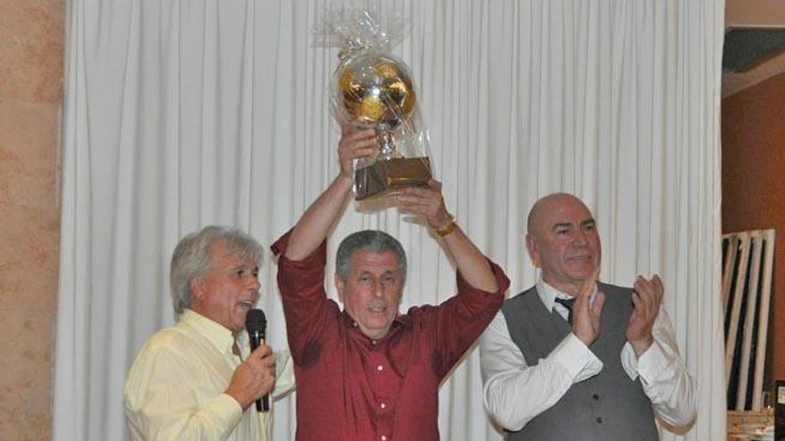 Miguelín levanta el balón de oro que le obsequiaron junto al presidente del Luchador, Fernando Roa, y Juan Mesa.